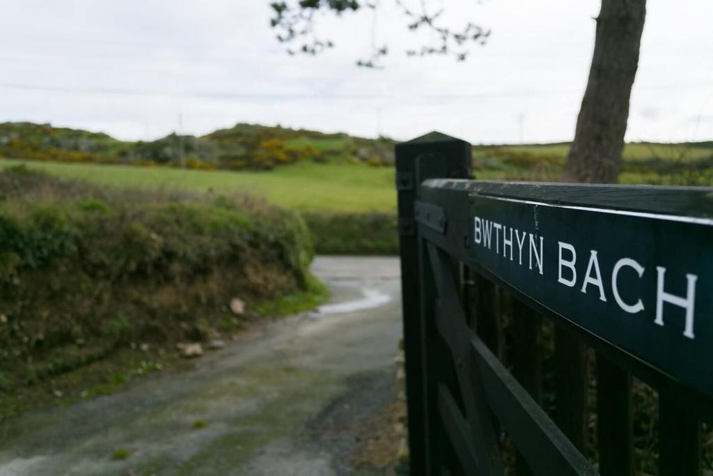 una puerta con las palabras playa británica en ella junto a una carretera en Bwthyn Bach en Llanrhyddlad