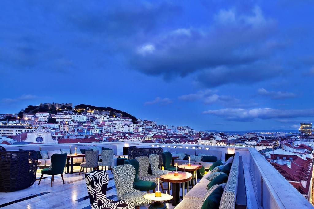 a balcony with tables and chairs and a view of a city at Altis Avenida Hotel in Lisbon