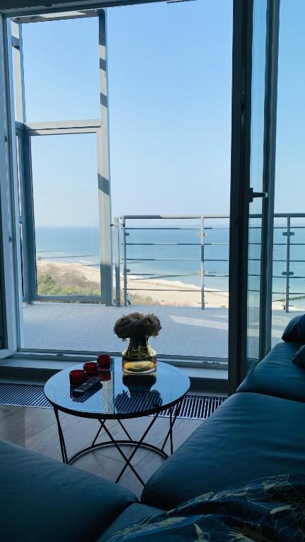 a living room with a table and a view of the ocean at The Baltic Horizon in Dziwnówek