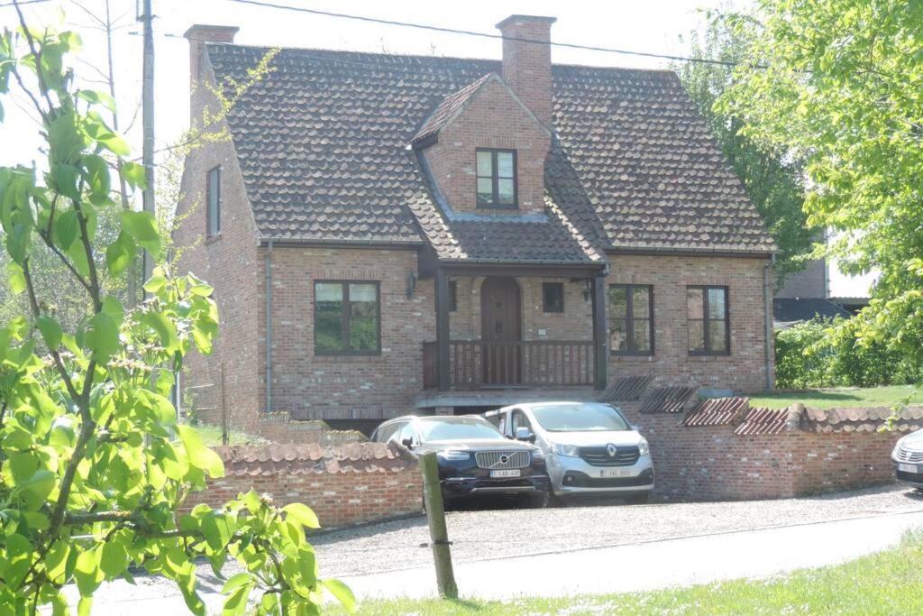two cars parked in front of a brick house at Vakantiewoning Zoetebeek in Oudenaarde