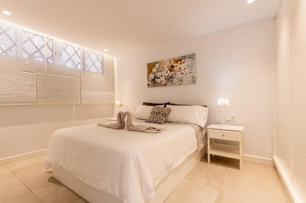 Habitación blanca con cama y mesita de noche en NEPTUNO 1A019, en Puerto de Santiago