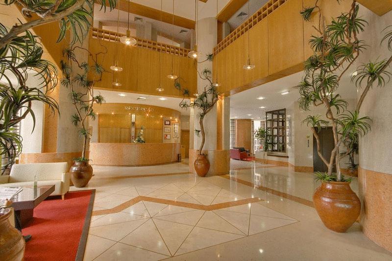 A bright double-height reception lobby filled with large potted plants.