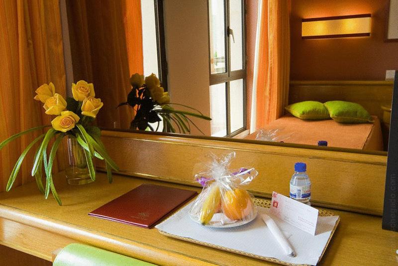A guest-room desk with a mirror, welcome snacks, and a narrow window.