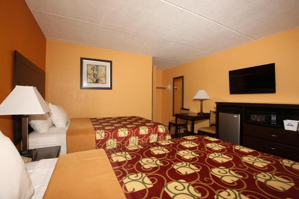 a hotel room with two beds and a flat screen tv at Budgetel Inn Glens Falls-Lake George-Saratoga in Glens Falls