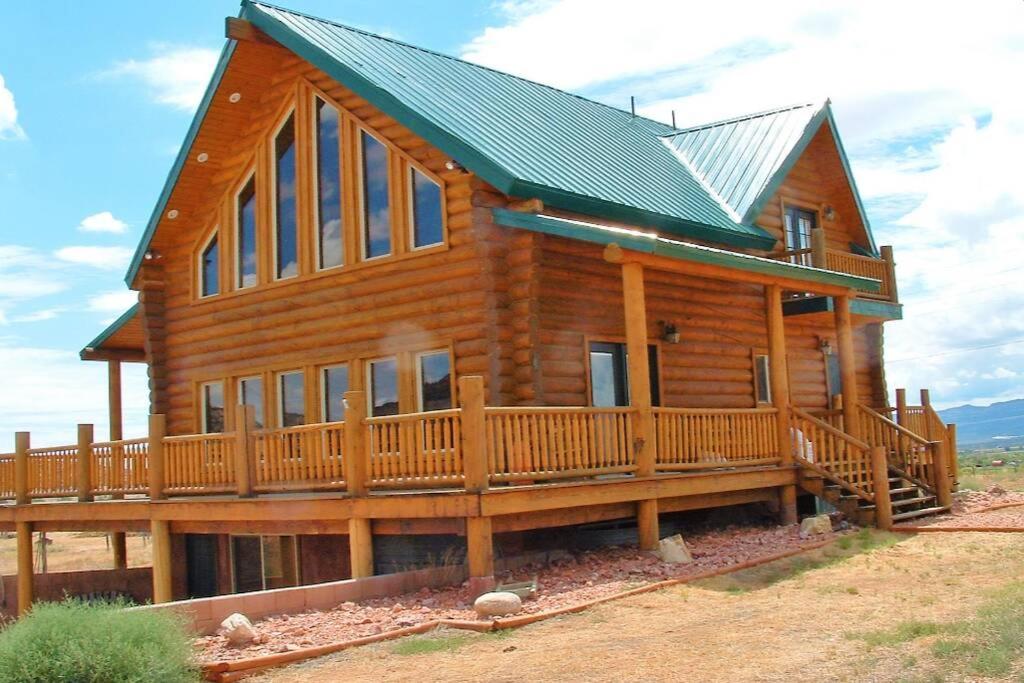 een groot houten huis met een groot terras bij Red Rock Ranch Log Cabin: Large, Fully Furnished in Escalante
