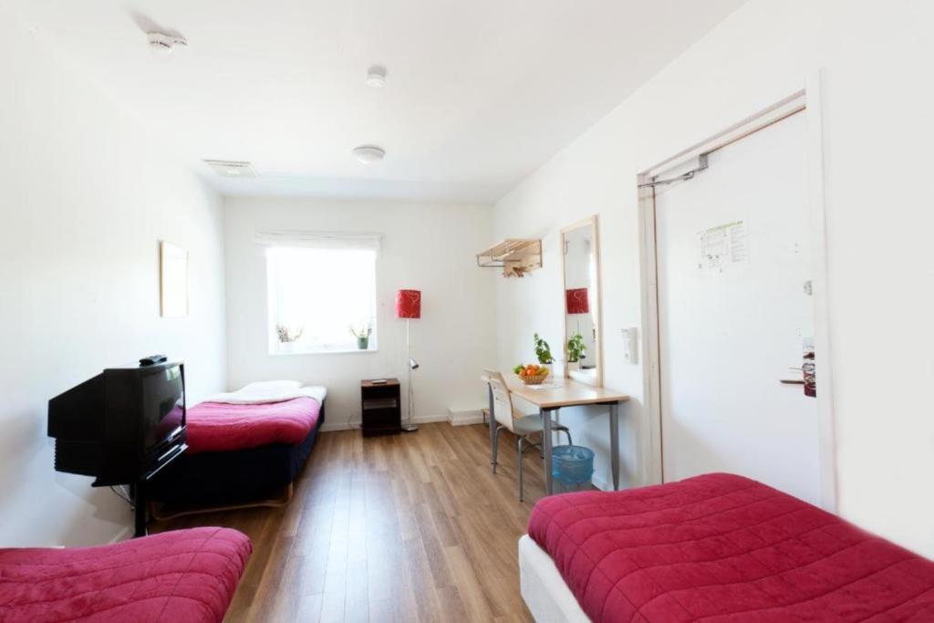 um quarto com duas camas e uma televisão e uma mesa em Vandrarhem Kvarntorget em Uppsala