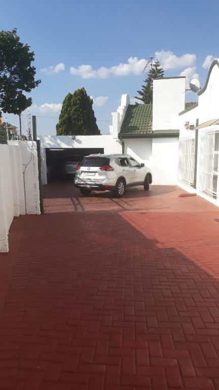 a car parked in a parking lot next to a house at Robertsham (Halaal) Self Catering Cottages 2 in Johannesburg