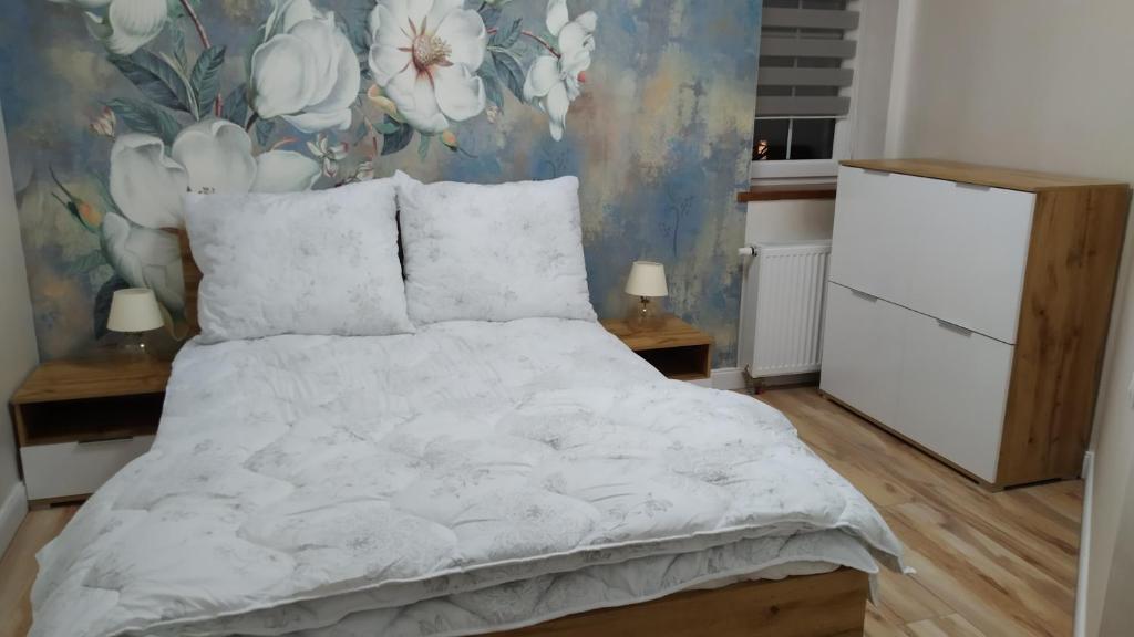 a bedroom with a white bed with a floral wallpaper at Apartamenty U Iwony Centrum miasta blisko Parku Zdrojowego in Kudowa-Zdrój