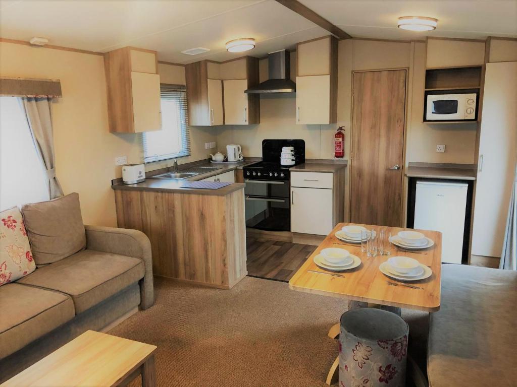 cocina y sala de estar con sofá y mesa en Laurel Superior Holiday Home en Mablethorpe