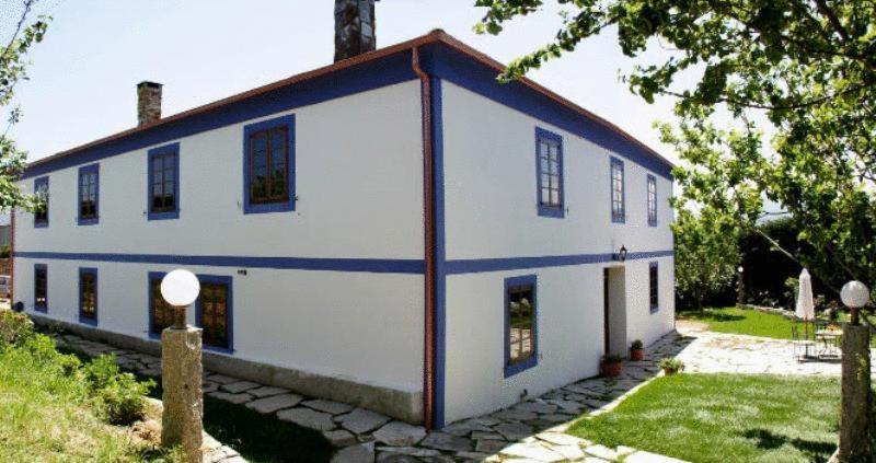 a white house with a red and blue roof at Casa Rural Vila Pomar in Ribadeo