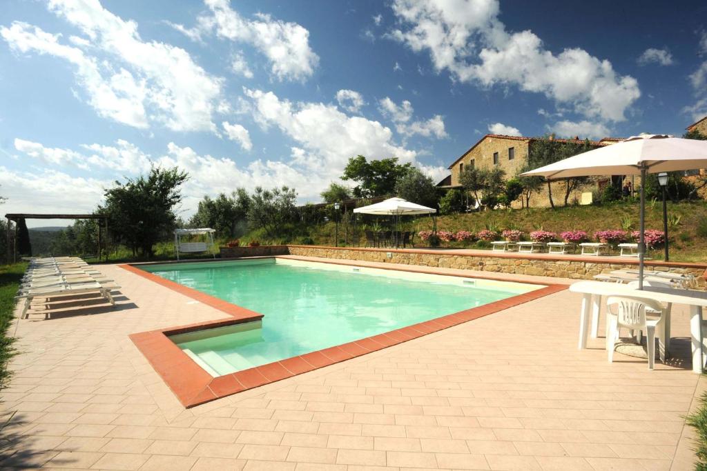 a swimming pool with chairs and an umbrella at Borgo Rapale in Rapale