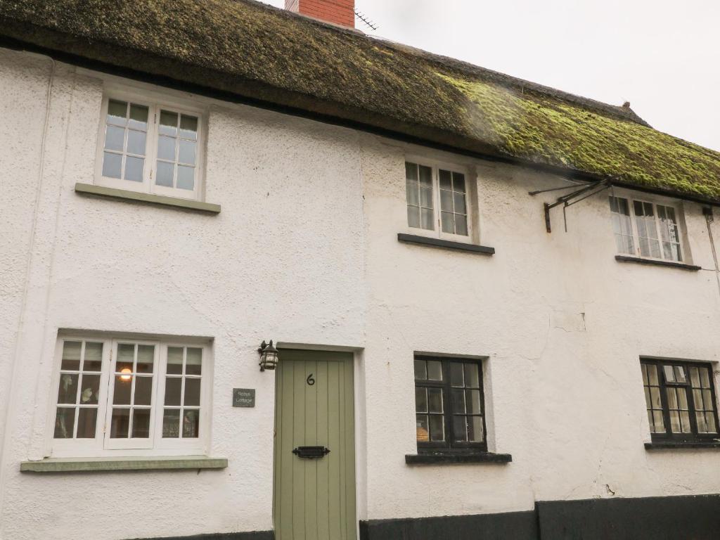 a white house with a green door and windows at Robyn Cottage in Budleigh Salterton