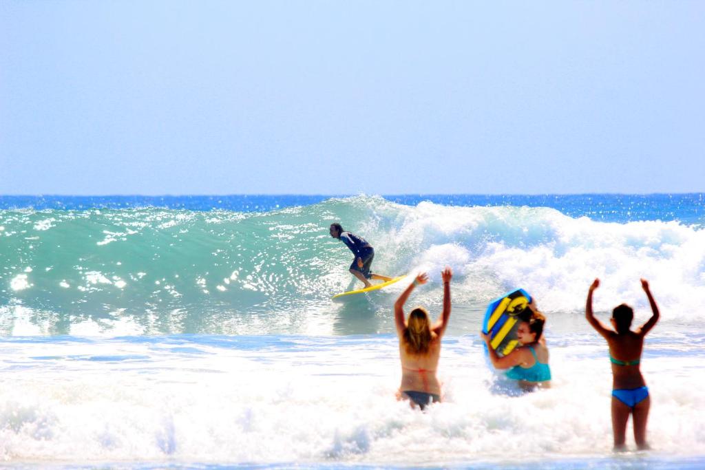 a group of people on the beach with a surfer on a wave at Cabo Surf Hotel in San José del Cabo