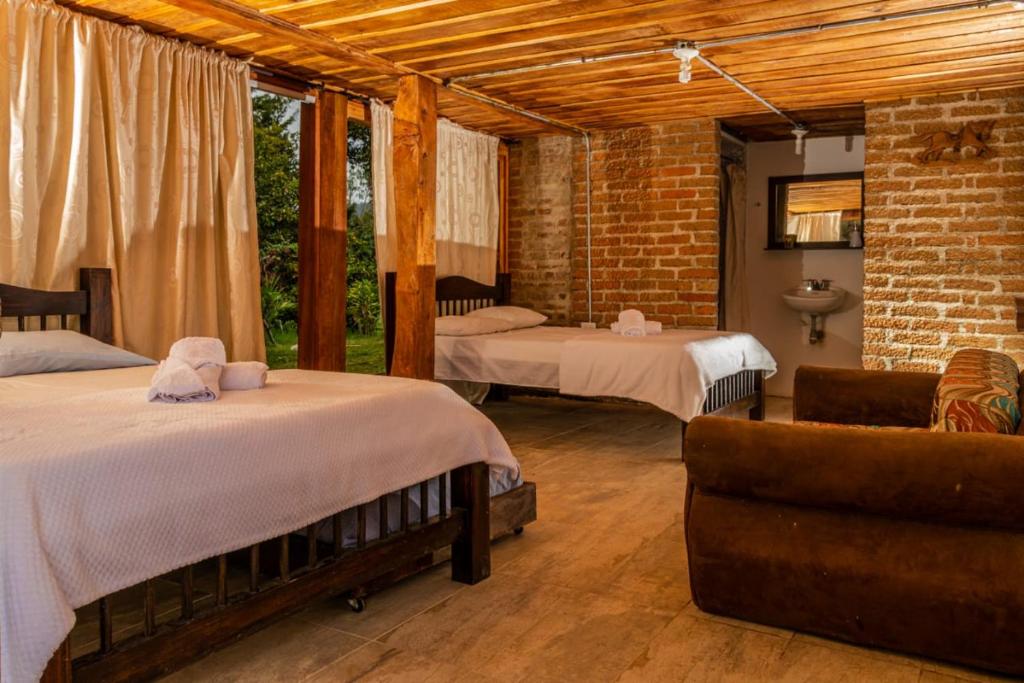 Una habitación con 2 camas y una silla en una habitación en Hostal rural la montaña alquiyapura, en Salento
