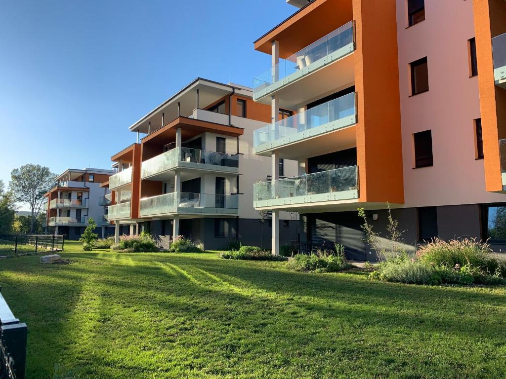 un edificio de apartamentos con césped delante en Fűzliget Mangó Terrace, en Balatonfűzfő