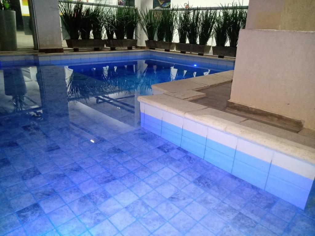 ein Pool mit blauen Lichtern in einem Gebäude in der Unterkunft Flat Olímpia com Área de Churrasqueira privada e tudo novo in Olímpia