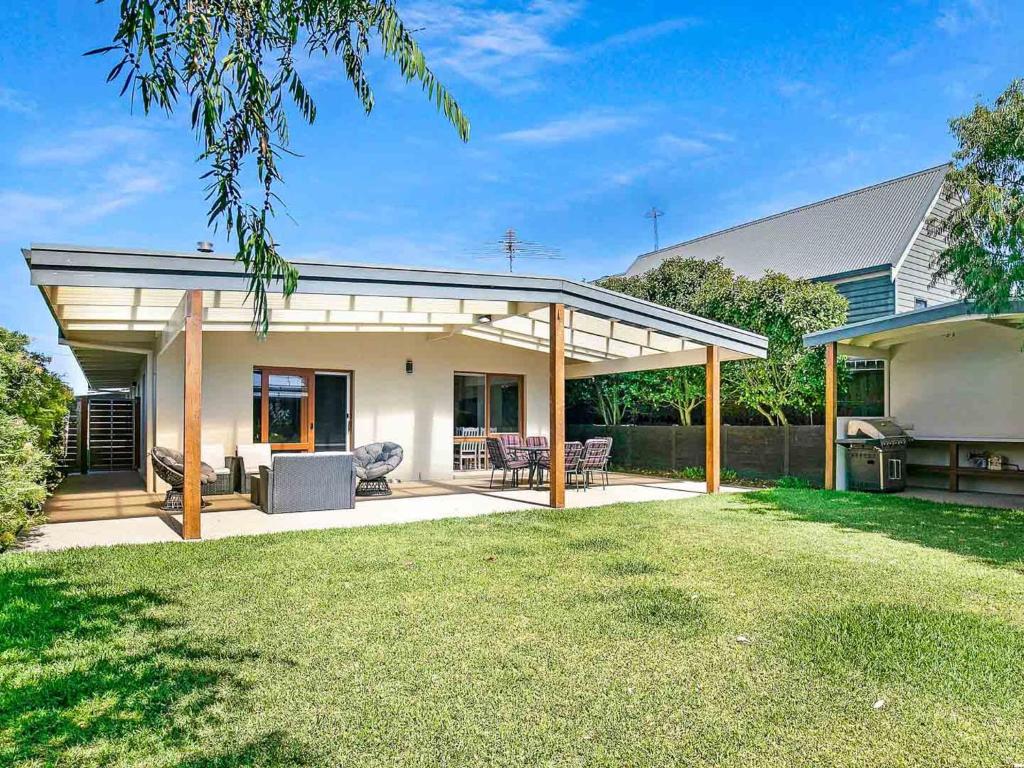 a house with a patio and a backyard with grass at Within Oceans Reach in Cape Woolamai