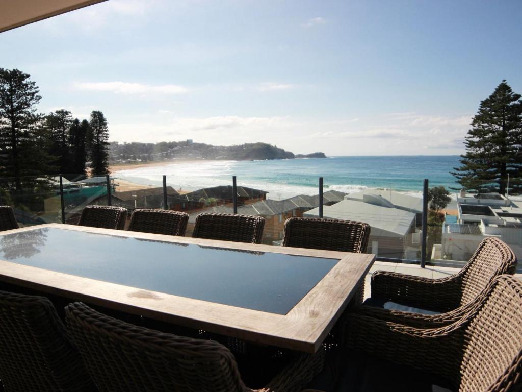 a table with chairs and a view of the beach at Beachside Holiday Home with Stunning Seaviews in Avoca Beach