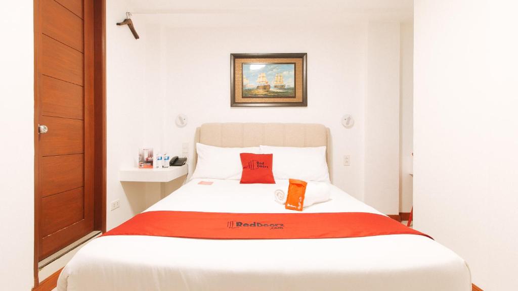 a bedroom with a white bed with a red blanket at RedDoorz near Mercado del Lago in Manila