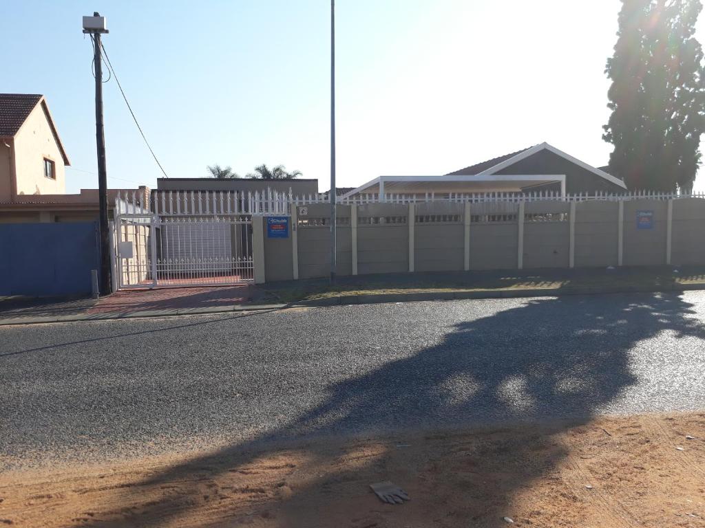 a fence on the side of a road next to a street at Robertsham (Halaal) Self Catering Cottages in Johannesburg