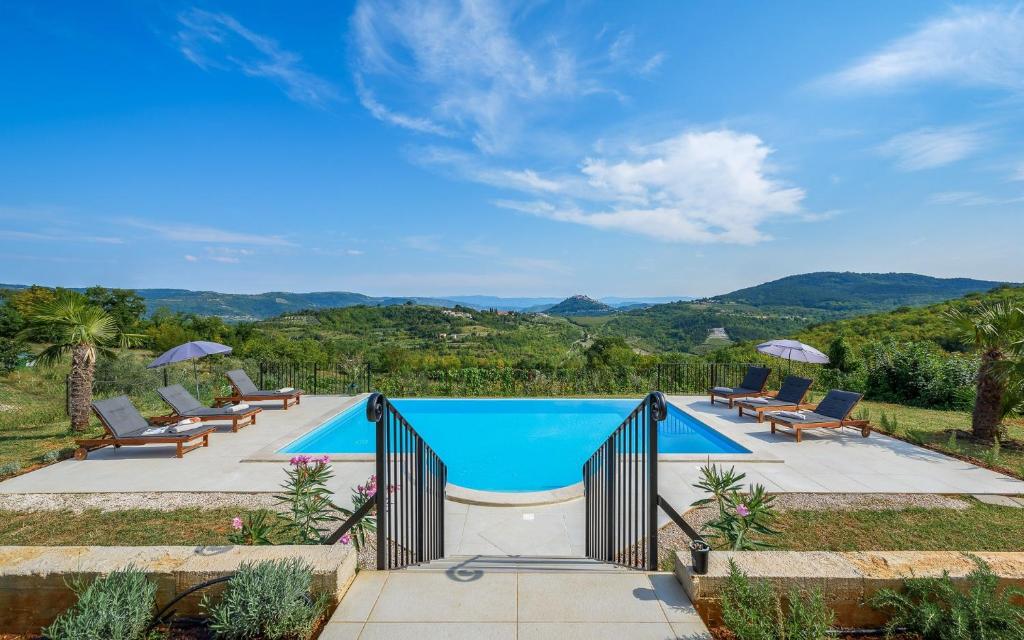 a swimming pool with chairs and a view of the mountains at Motovun view villa in Motovun