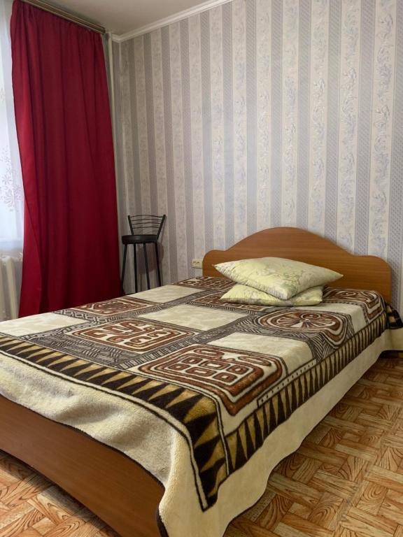 Дуванский бульвар 23 في أوفا: سرير في غرفة نوم مع ستارة حمراء