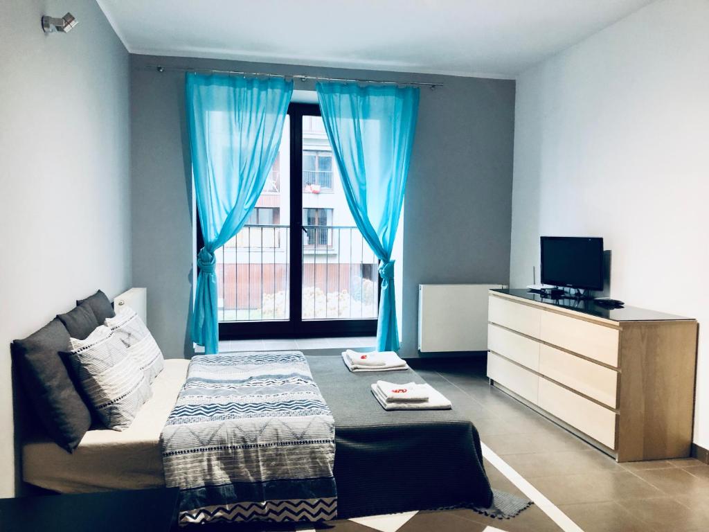a bedroom with a bed and a window with blue curtains at Blue River - Walonska 9 - private Apartment in Wrocław