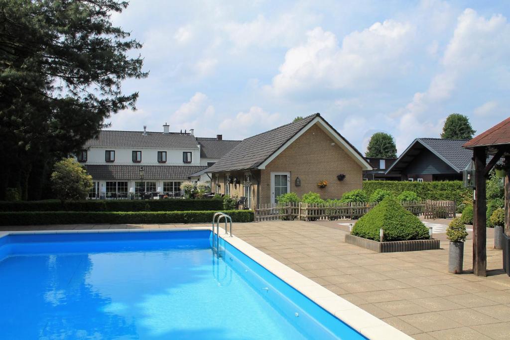 a swimming pool in front of a house at Hotel Handelia in Handel