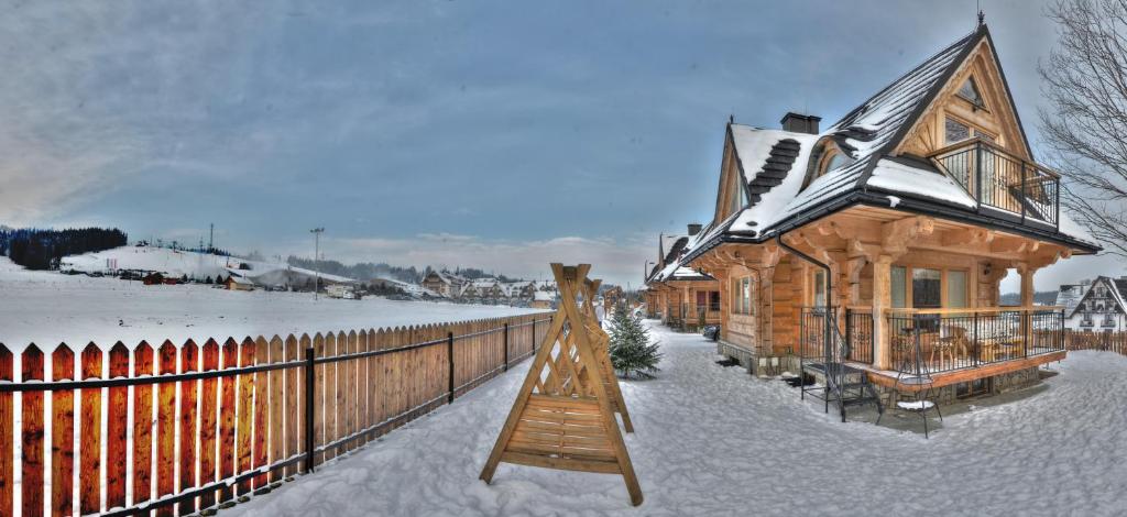 a log cabin in the snow with a wooden fence at Domki Bania in Białka Tatrzańska