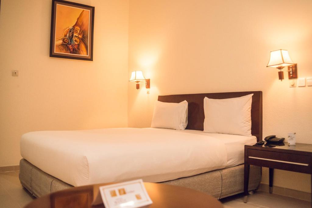 um quarto de hotel com uma cama grande e uma mesa em Hôtel Sancta Maria em Lomé