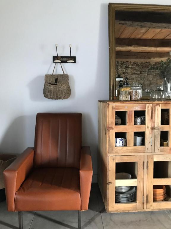 a brown leather chair sitting next to a wooden cabinet at Le Mottay Guesthouse in Saint-Père-en-Retz
