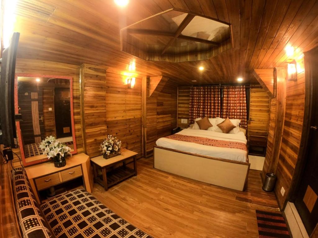 een slaapkamer met een bed in een houten hut bij Hotel Broadway Anneexy in Darjeeling