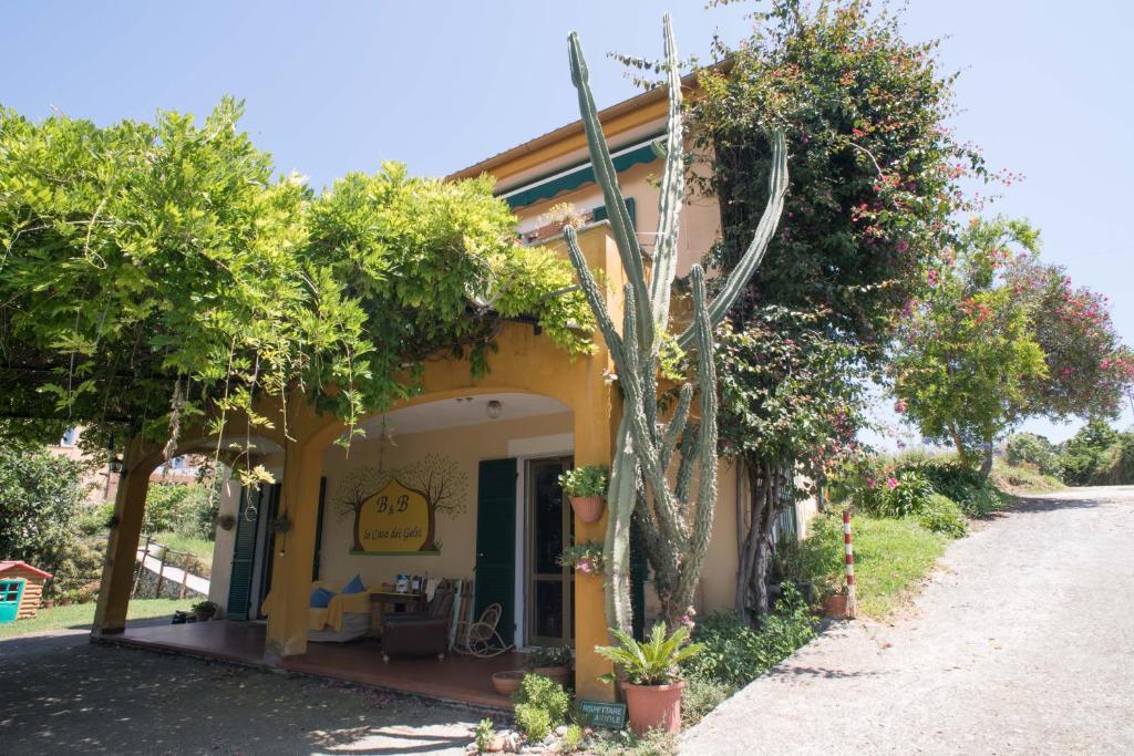 ein gelbes Gebäude mit Bäumen und Pflanzen davor in der Unterkunft B&B La casa dei gelsi in Loano