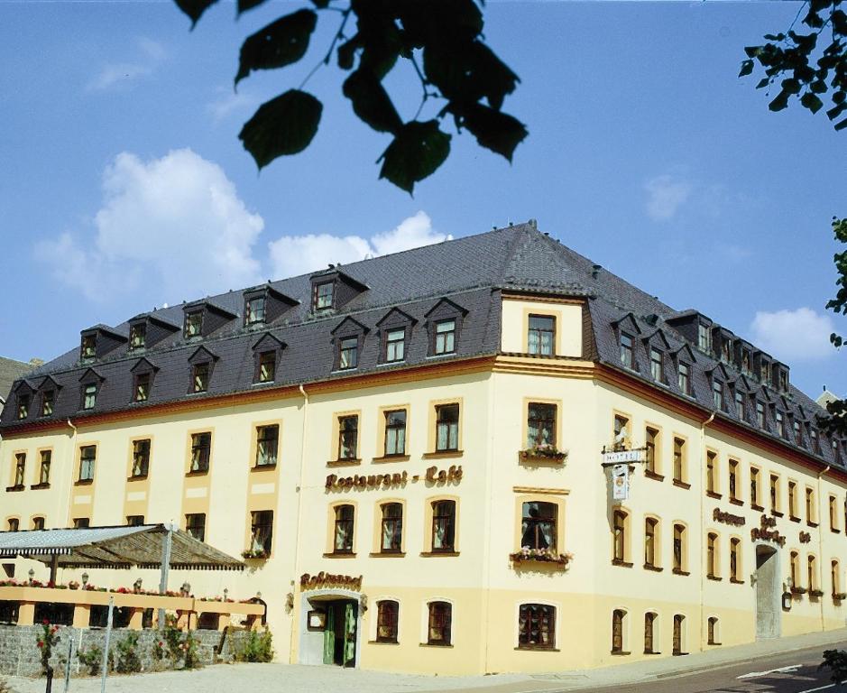 ein großes gelbes Gebäude mit schwarzem Dach in der Unterkunft Hotel Weißes Roß in Marienberg