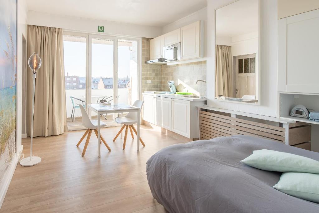 1 dormitorio con cama, mesa y cocina en Studio Le Lavandou, en De Panne