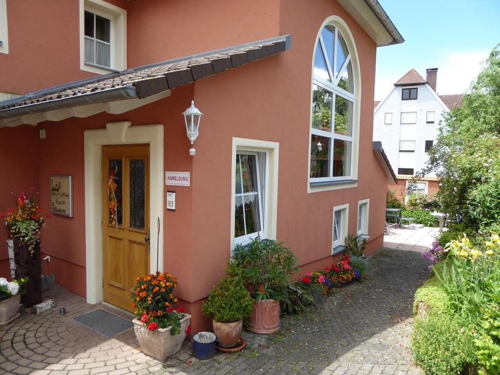 a red house with flowers in pots in front of it at Pension Rosengärtchen in Absberg