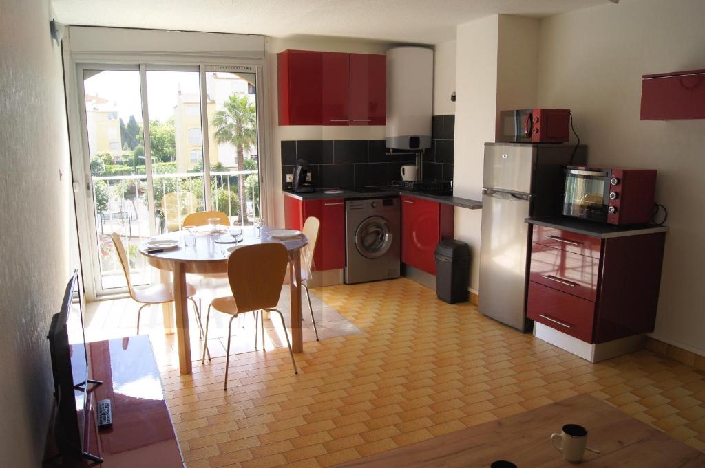 une cuisine avec des placards rouges et une table avec des chaises dans l'établissement Lara 5 - Grand T2 sans vis-à-vis Parking - Près centre-port, île des Loisirs, plage Richelieu, au Cap d'Agde