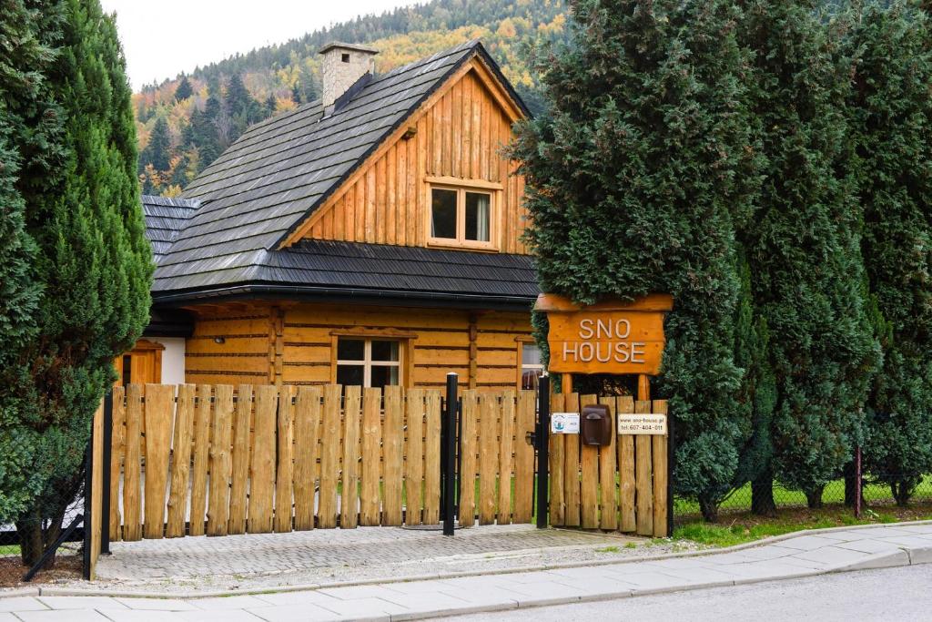 a wooden house with a sign in front of a fence at Sno House in Szczyrk