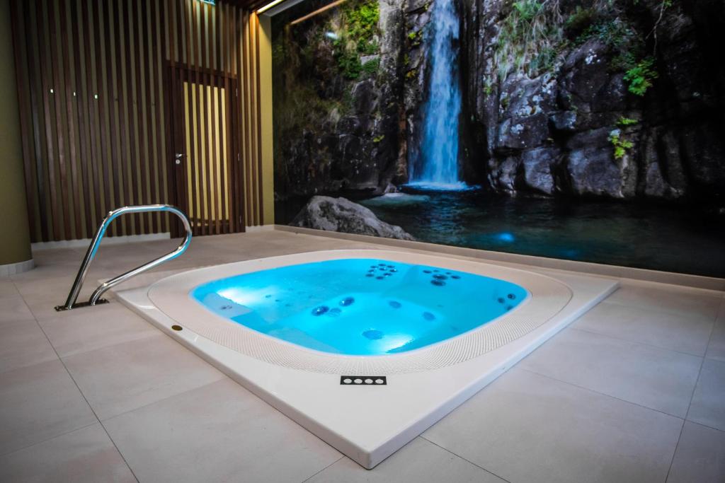 a jacuzzi tub in a bathroom with a waterfall mural at Hotel São Bento da Porta Aberta & Spa in Geres