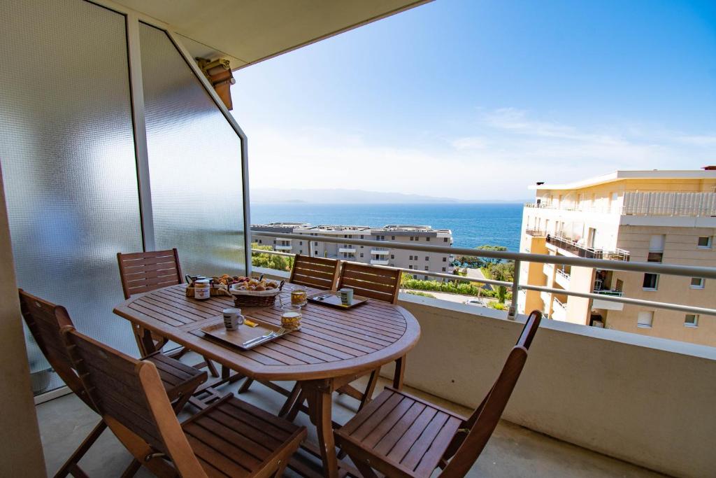 een tafel en stoelen op een balkon met uitzicht op de oceaan bij Cappella in Ajaccio