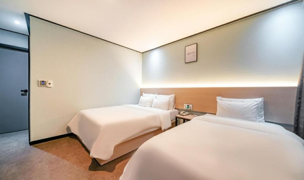 um quarto de hotel com duas camas e um espelho em Hotel The May em Busan