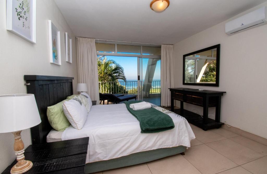 a bedroom with a bed and a desk and a window at 17 Kyalanga Umhlanga Rocks in Durban