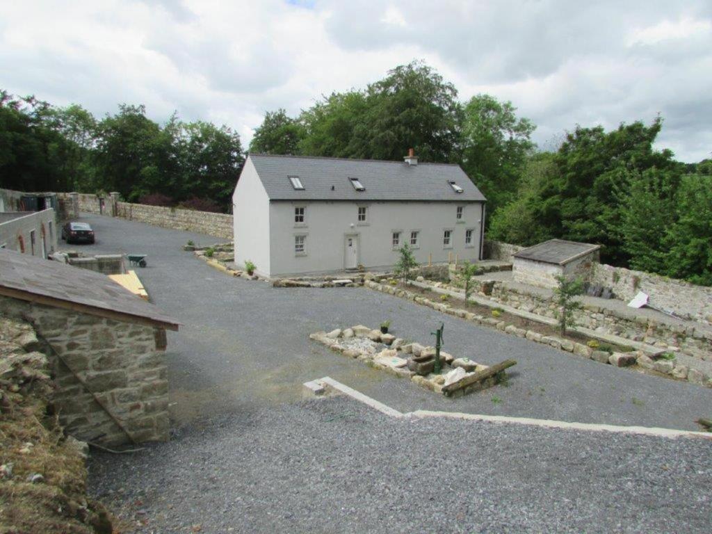 a large white building in a parking lot at Lovely 3-Bed House at Clashganny Mill Borris in Carlow