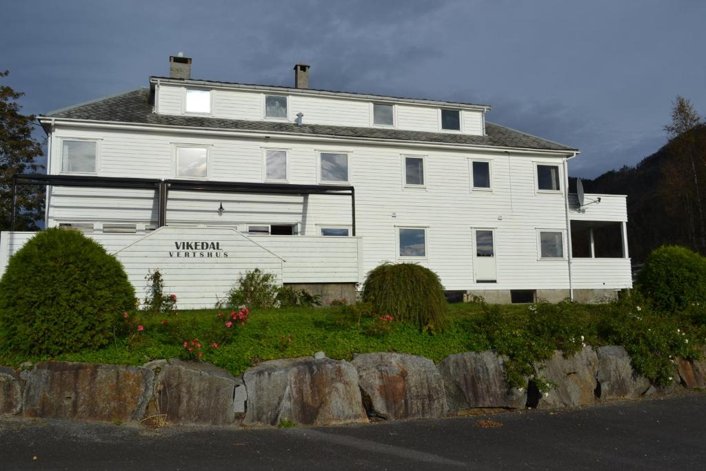 uma grande casa branca no topo de uma colina em VIKEDAL VERTSHUS hotel em Vikedal