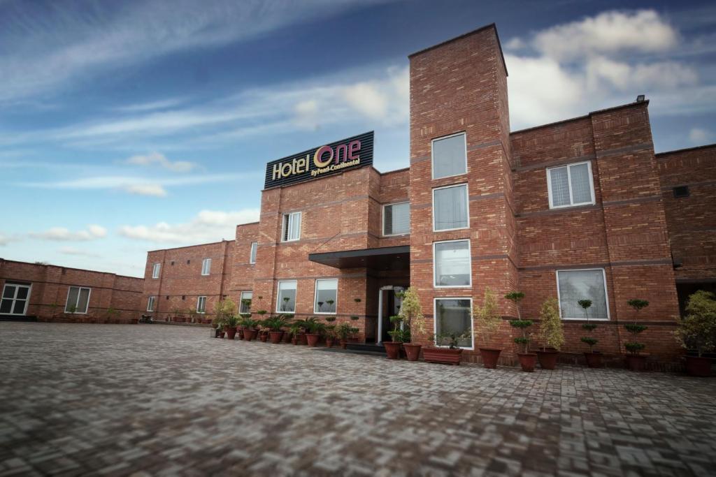 a red brick building with a sign on it at Hotel One Sahiwal in Sāhīwāl