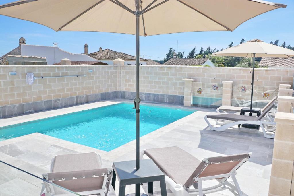 a pool with two chairs and an umbrella next to it at Chalet Puente Tabla in Conil de la Frontera