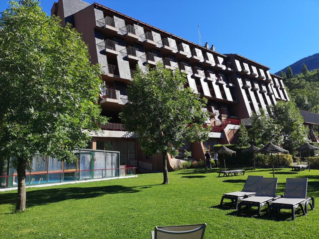 a large building with chairs and trees in front of it at Evenia Monte Alba in Cerler