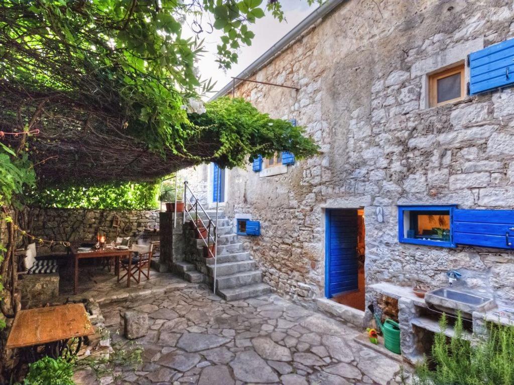 a stone house with a staircase leading up to a building at 450 year-old house with a garden in Stari Grad