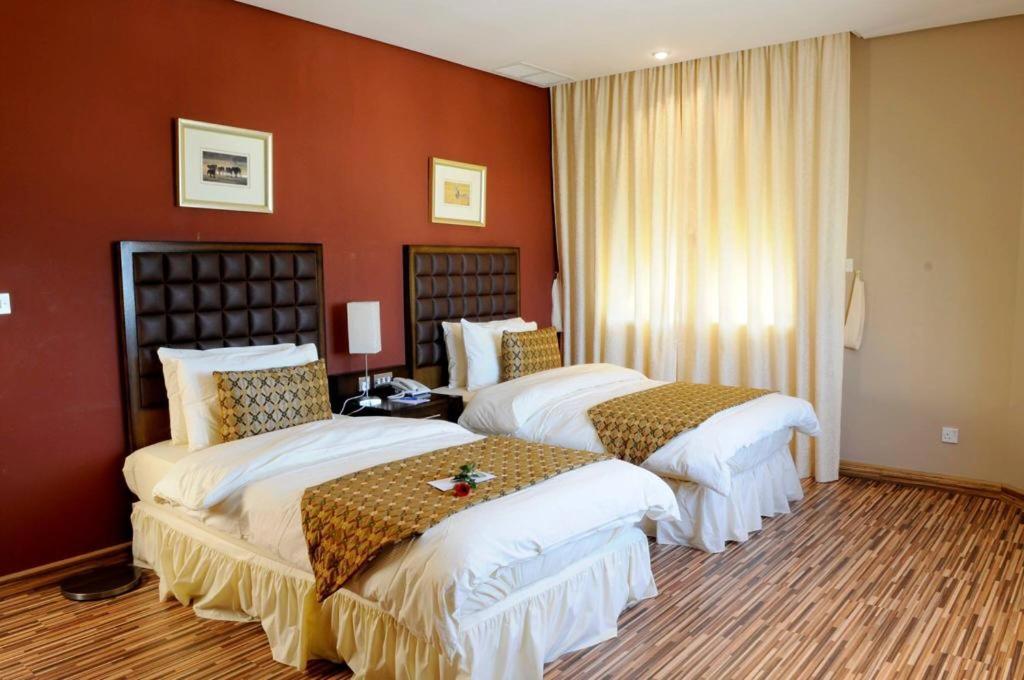 Spice Hotel في الكويت: سريرين في غرفة الفندق بجدران حمراء