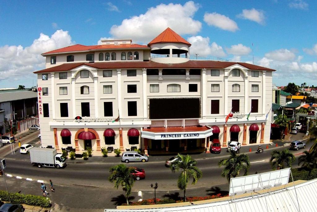 a large white building with a red roof on a street at Ramada by Wyndham Princess Paramaribo in Paramaribo